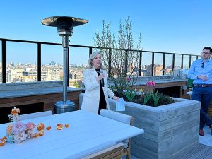 Allyson Hansen speaks on The Lydian rooftop with microphone and blue sky