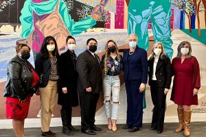 CEO and Executive Director Allyson Hansen with Toni Preckwinkle, Israel Rocha Jr, others, standing in front of large colorful mural